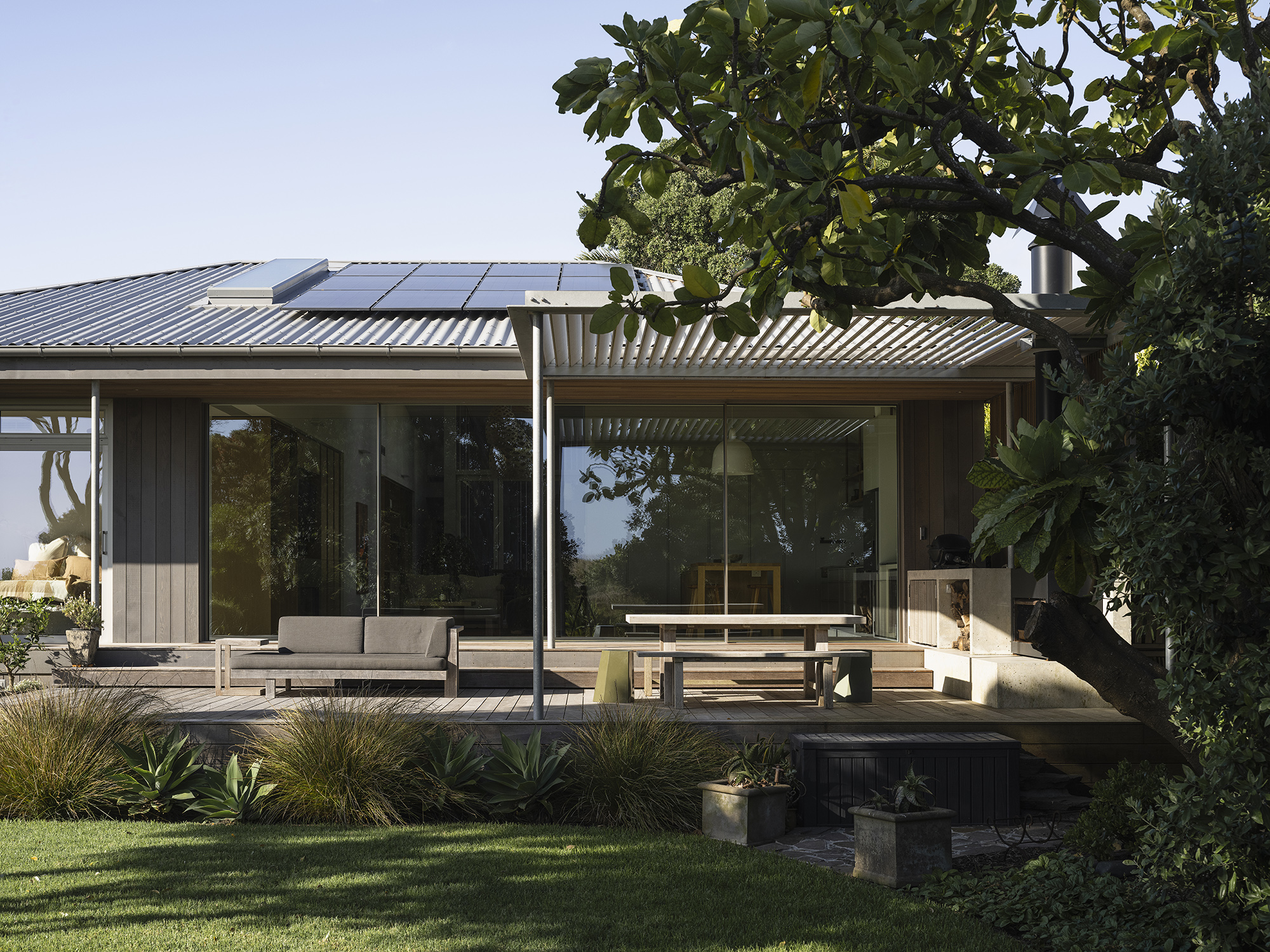 Treefold deck and outdoor lounge — long roof, screened canopy, native planting in the foreground